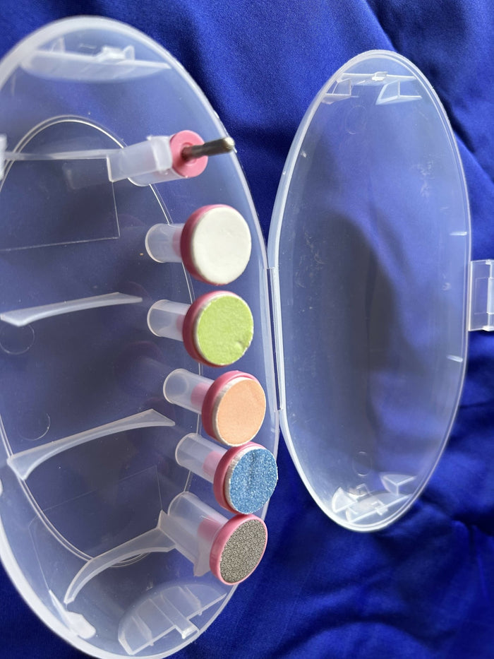 Clear nail drill with colored attachments on a blue background