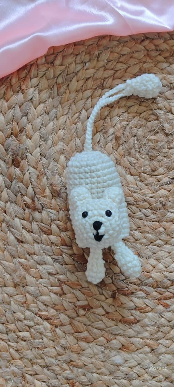 White crocheted mouse toy on a woven surface