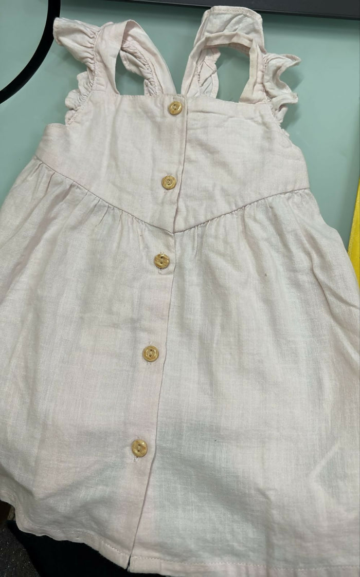 Light-colored dress with button details on a light blue background