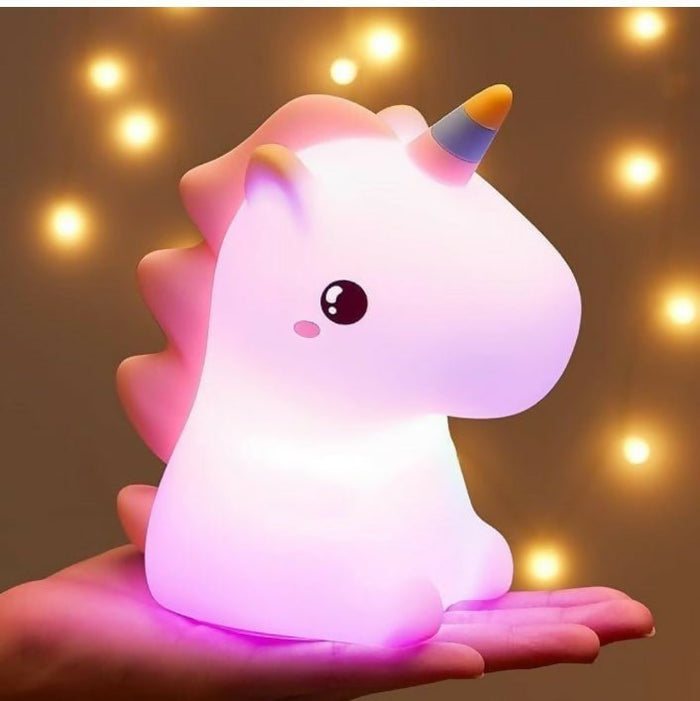 Unicorn-shaped night light glowing on a hand with a warm, blurred background