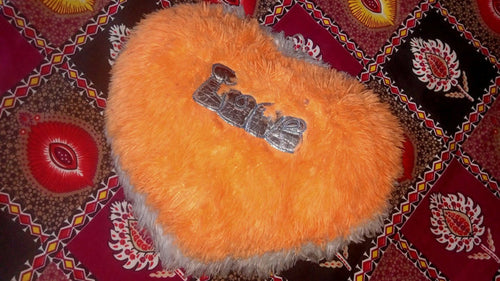Orange fluffy object with a metal clip on a patterned fabric background