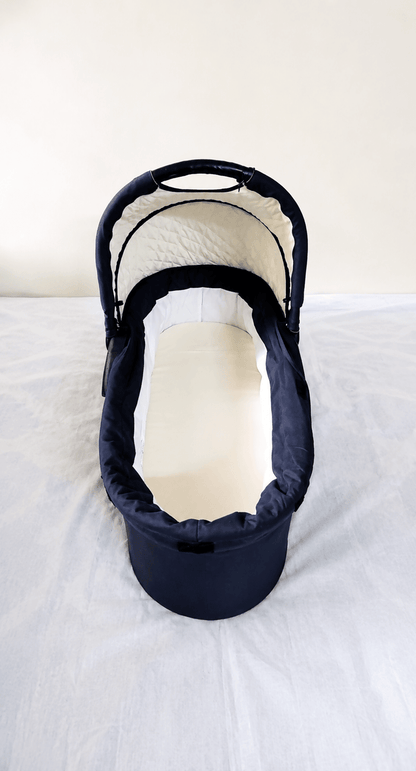 babycab Noah Carrycot Bassinet in Navy Blue, designed as a stroller attachment with a comfortable padded interior, protective canopy, sturdy construction, and cozy lie-flat space for newborns and young infants.