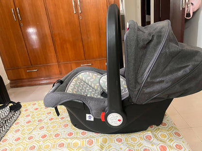 Babyhug Car Seat Cum Carry Cot with rocking base for newborns, rear-facing infant car seat featuring a 5-point safety harness, ergonomic carry handle, padded seat, and removable canopy for safe travel and comfortable carrying.