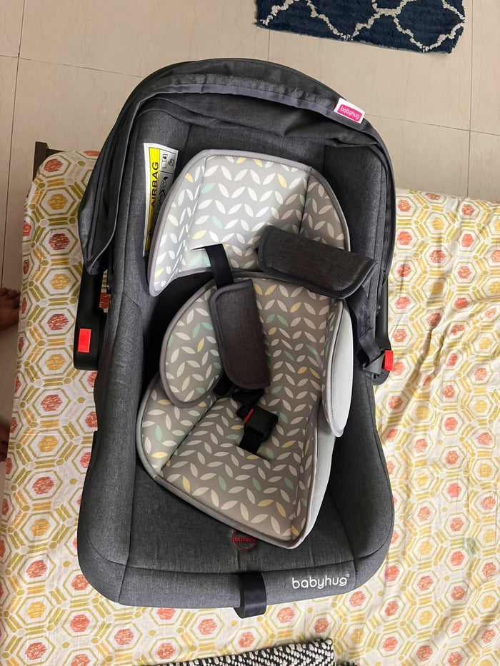 Babyhug Car Seat Cum Carry Cot with rocking base for newborns, rear-facing infant car seat featuring a 5-point safety harness, ergonomic carry handle, padded seat, and removable canopy for safe travel and comfortable carrying.