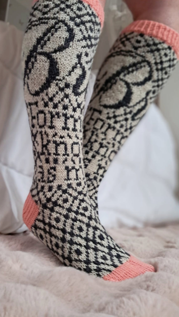 Patterned socks with pink accents worn on a white surface