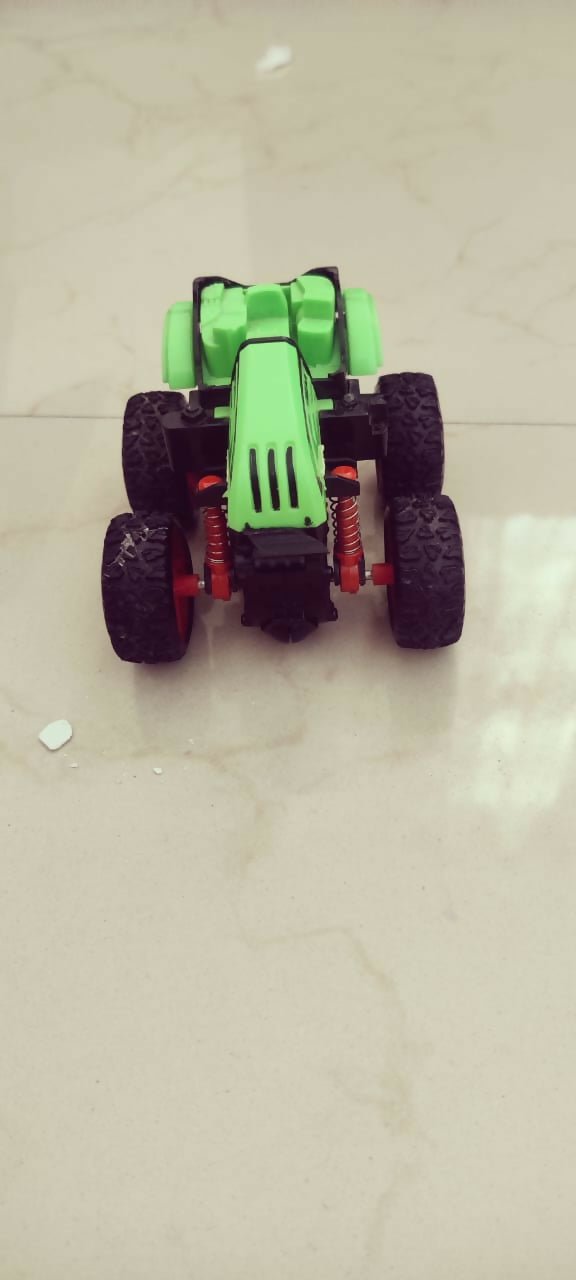 Green toy truck with large wheels on a light-colored floor