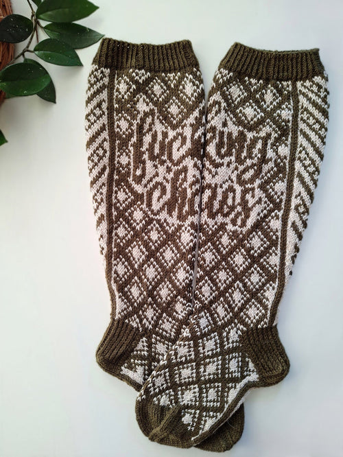 Pair of brown and white patterned socks with the text Fucking Chaos on a light background