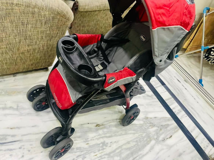 Red and gray stroller on a marble floor with a couch in the background