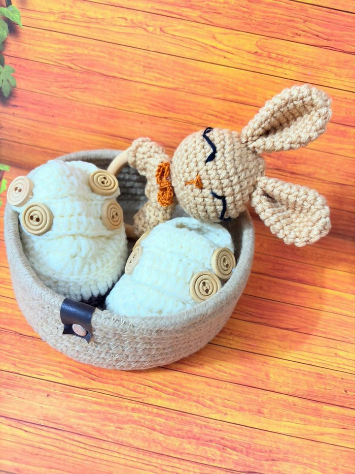 Knitted bunny toy with button details in a basket on a wooden surface