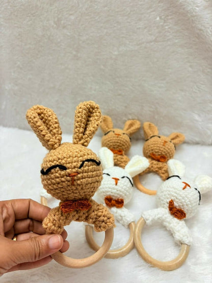 Set of crochet bunny toys with wooden rings on a textured surface