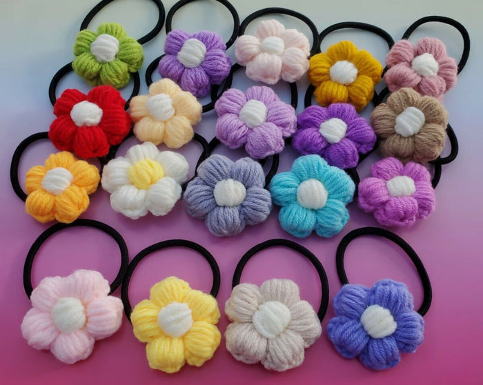 Colorful knitted flower hair ties on a pink background