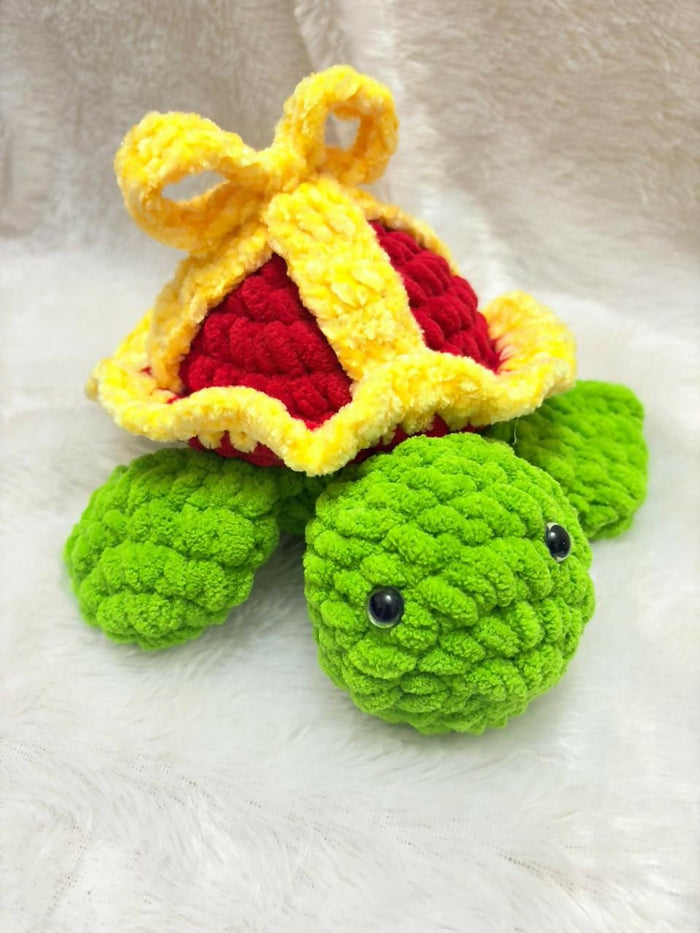 Crocheted turtle toy with a crown on a white background