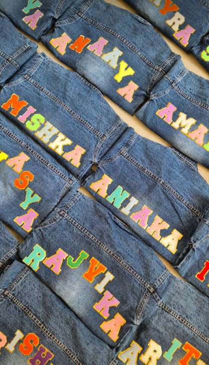 Denim jackets with colorful text labels on a flat surface
