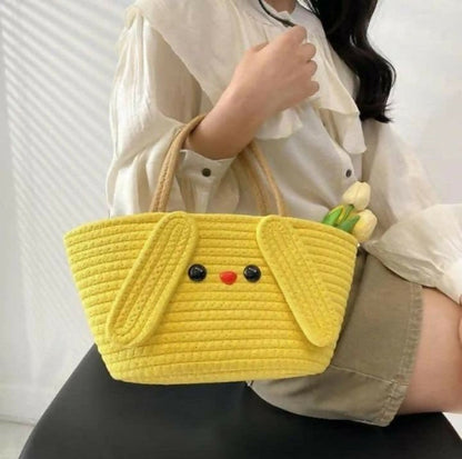Person holding a yellow quilted handbag with a face design against a white background