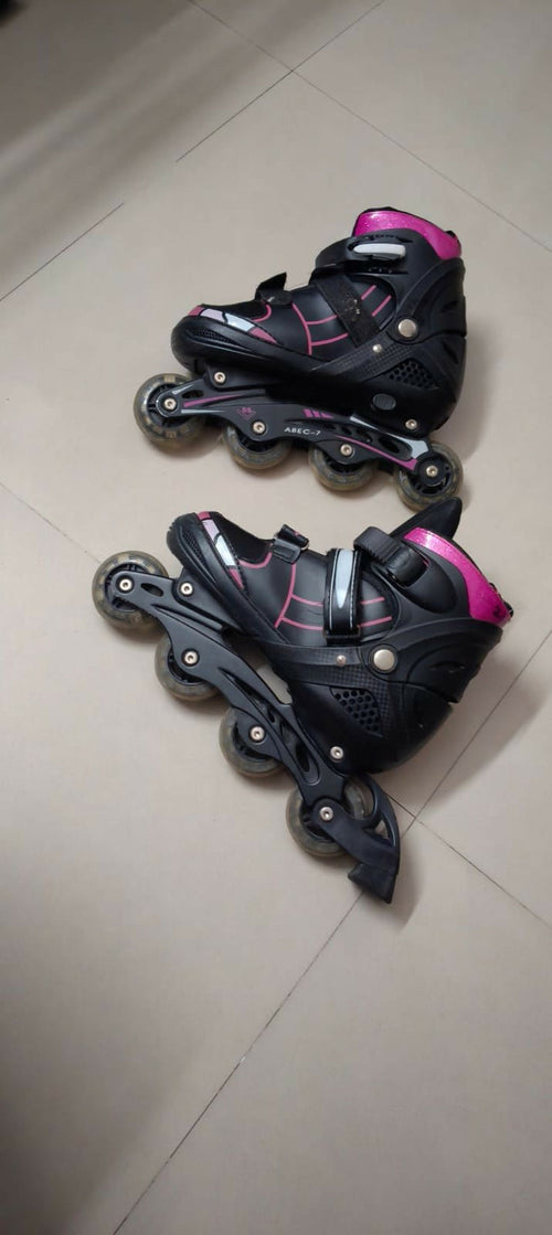 Pair of black and pink inline skates on a tiled floor