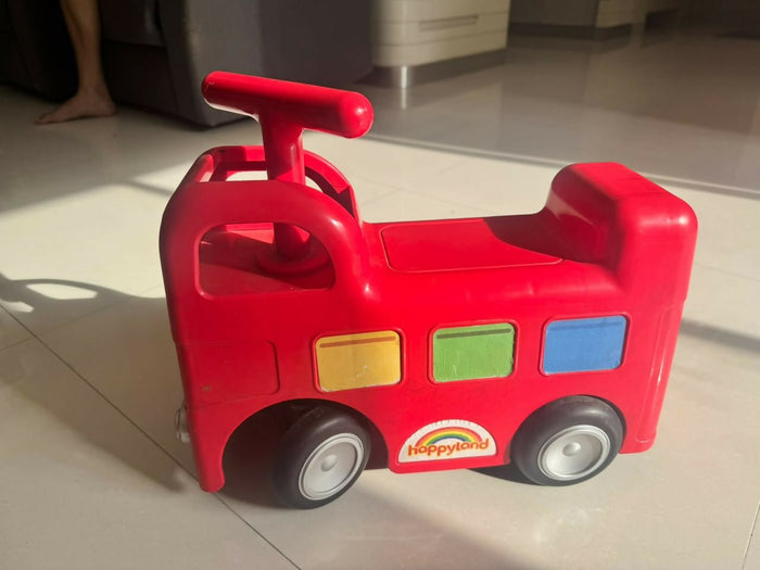 ELC Happyland Ride-On Bus with a colorful bus-inspired design, comfortable seat, sturdy wheels, easy-grip steering handle, and durable construction for fun indoor and outdoor riding play.