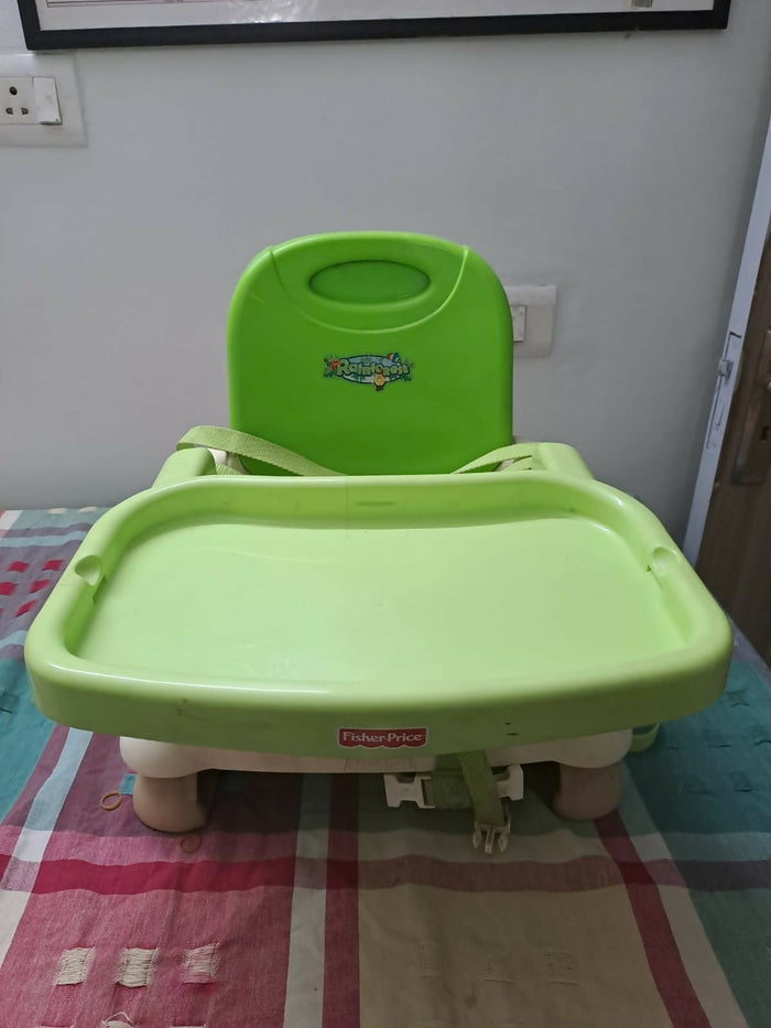 Green high chair on a checkered floor with a white wall background