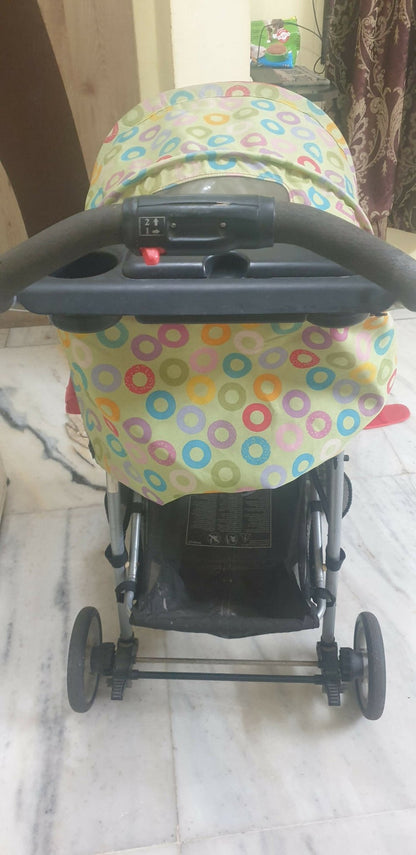 Stroller with a colorful canopy on a marble floor.