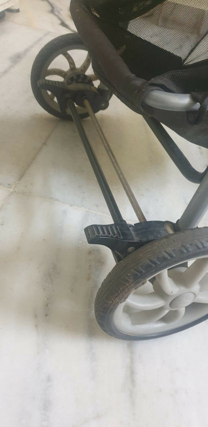 Close-up of a stroller wheel and metal frame on a light background