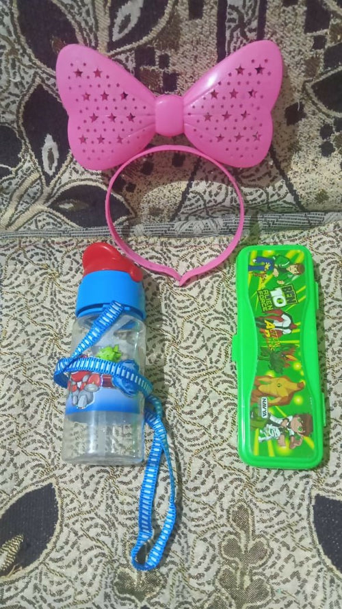 Pink bow headband, blue water bottle with straw, and green cartoon-themed box on a patterned surface