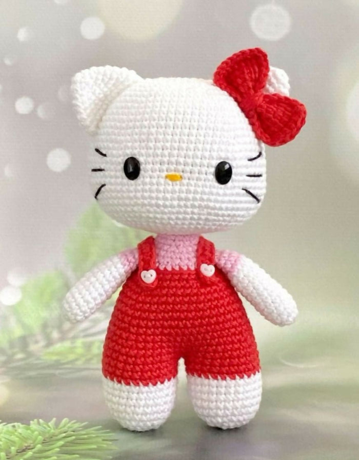 Crocheted toy resembling a character with a red bow and white outfit on a light background