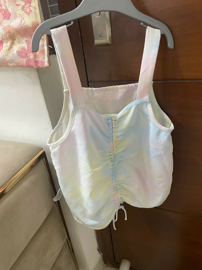Pastel-colored baby romper on a hanger against a wooden door.
