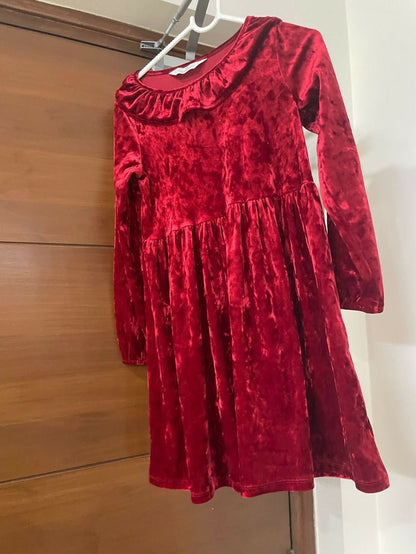 Red velvet dress on a hanger against a wooden door background