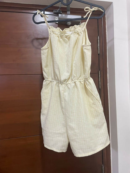 Light yellow romper hanging on a wooden door