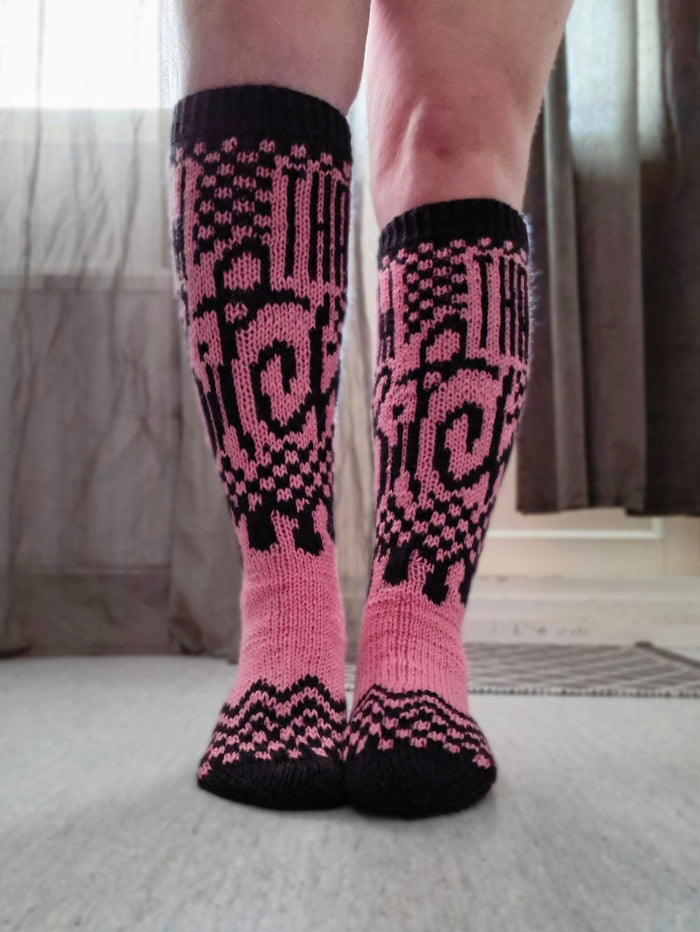 Pink and black patterned socks worn by a person on a neutral background