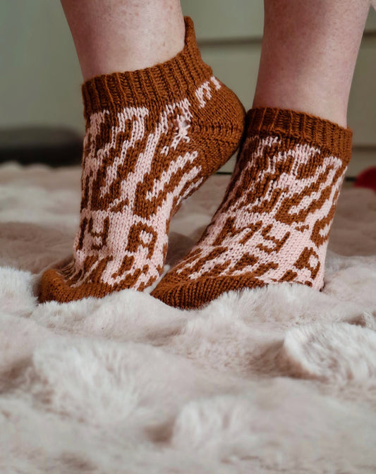 Brown and white patterned socks on a fluffy white surface