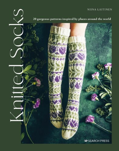 A book cover of 'Knitted Socks' by Niina Laitinen featuring a pair of knitted socks with a floral pattern in purple, green, and white colors, placed against a background with cut flowers.
