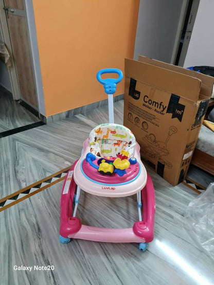 Pink and blue baby walker on a marble floor with a cardboard box labeled 'Comfy' in the background.