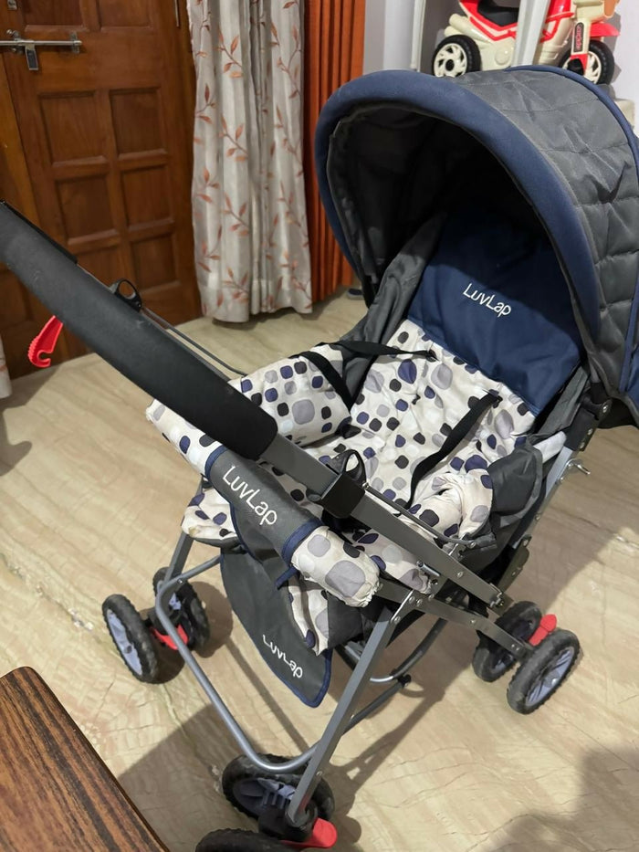 Stroller with a patterned bag on a wooden floor, with a door and curtain in the background.