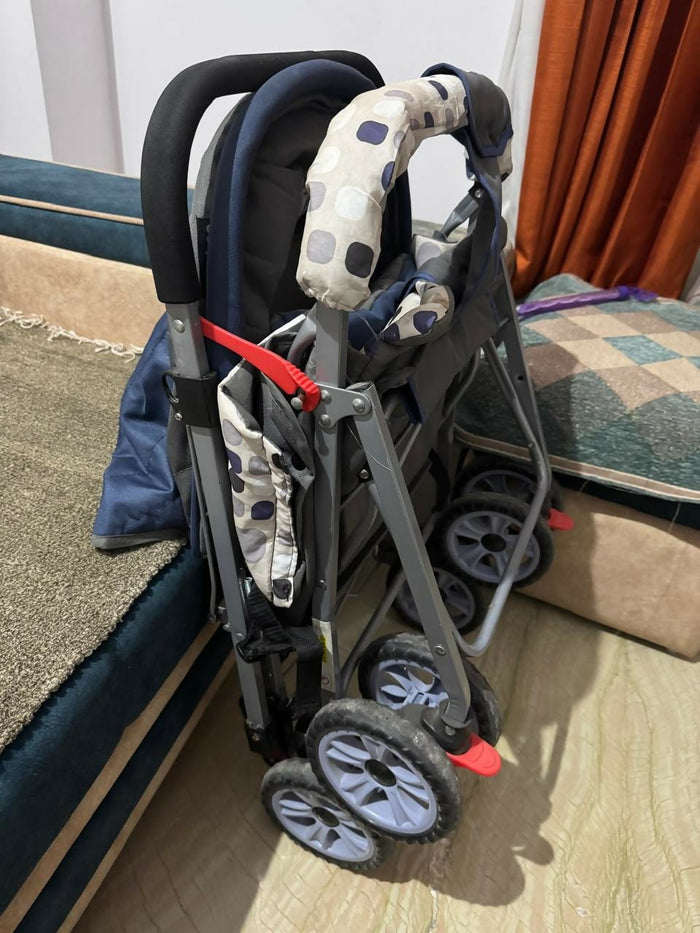Foldable stroller with patterned seat cover on a wooden floor.