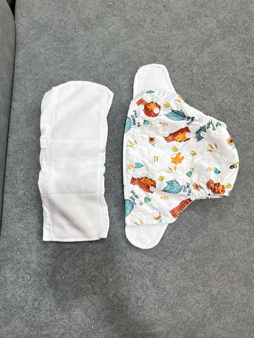 Two baby diapers on a gray surface, one plain and one with colorful designs.