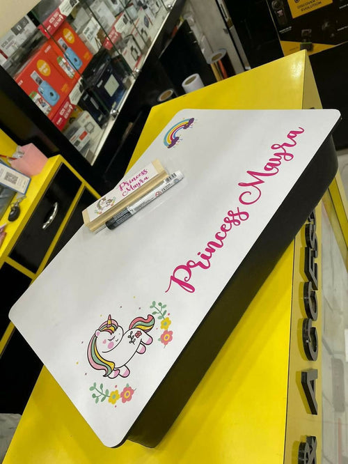 Children's desk mat with unicorn design and 'Princess Maria' text on a yellow surface.