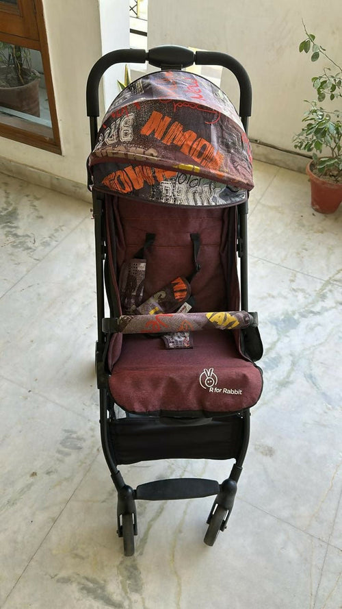 Red baby stroller with camouflage pattern on a marble floor