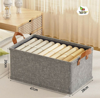 Gray storage basket with handles containing rolled-up items, placed on a bed with measurements indicated.