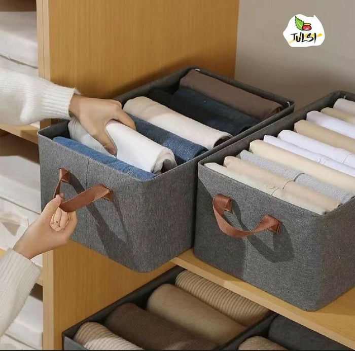 Gray storage bins with handles containing folded clothes inside a wooden drawer, brand 'TULSI' visible.